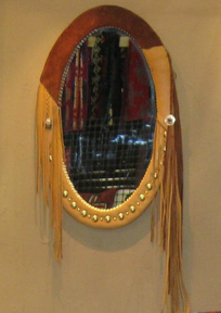 Oval mirror with leather wrapping, brass studs and extended fringe.