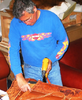 Photo of ernie apodaca installing leather over chair frame.